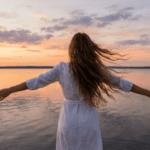 湖畔で両手を広げる女性